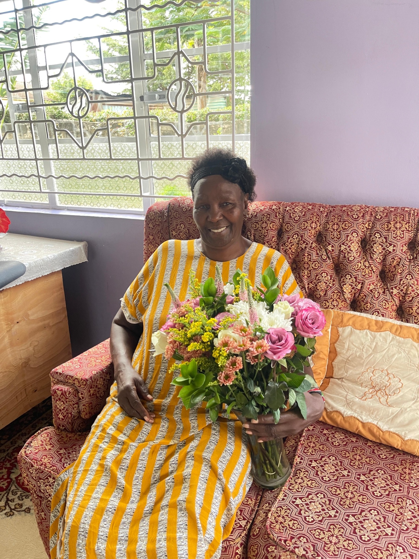 Mama Joy at home in Nairobi, holding flowers