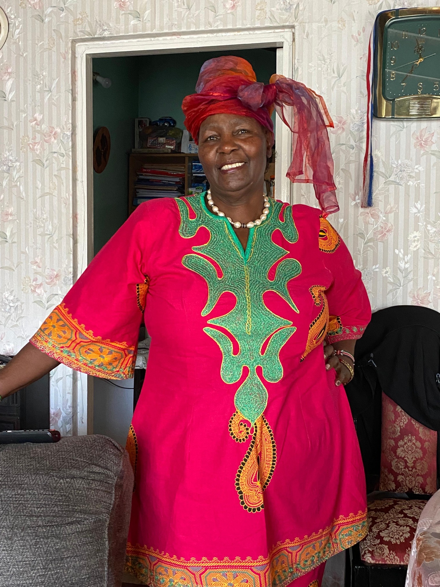 Portrait of Mama Joy in a vibrant pink dress and colorful head wrap